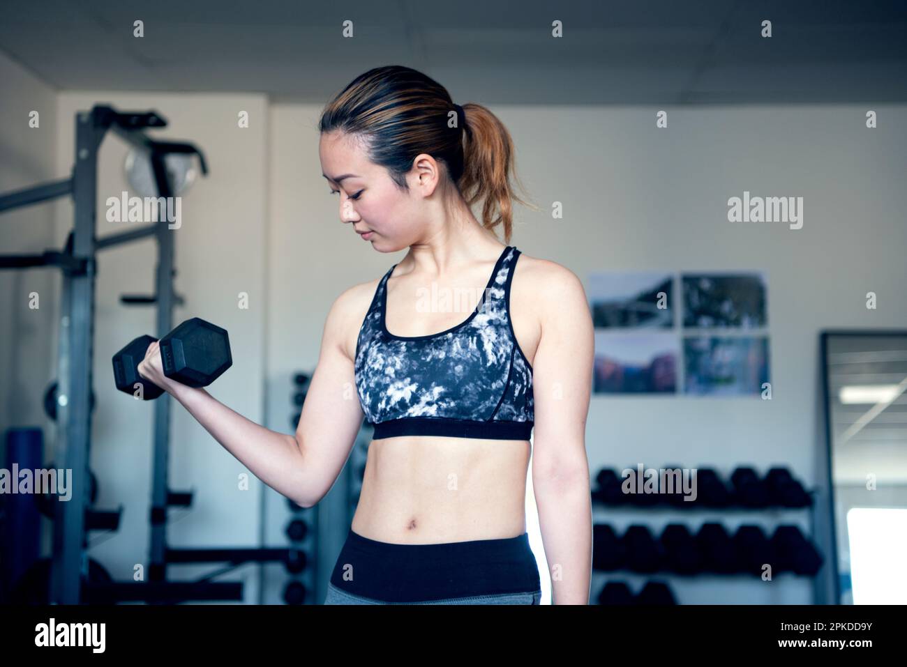 Femme faisant l'entraînement de force avec des haltères à la salle de gym Banque D'Images