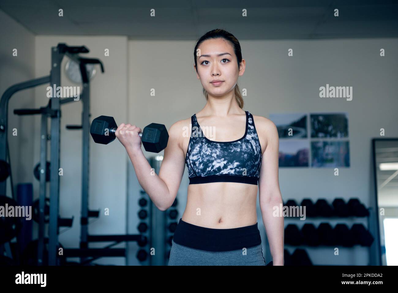 Femme faisant l'entraînement de force avec des haltères à la salle de gym Banque D'Images