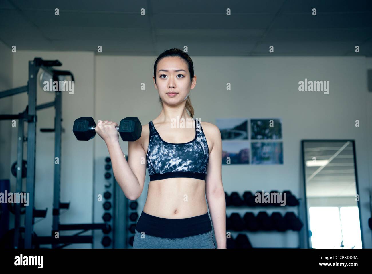 Femme faisant l'entraînement de force avec des haltères à la salle de gym Banque D'Images