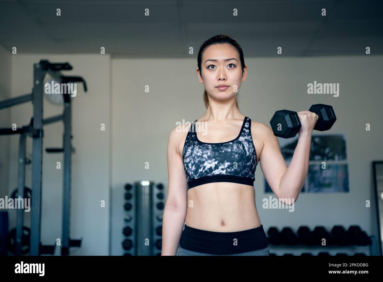 Femme faisant l'entraînement de force avec des haltères à la salle de gym Banque D'Images