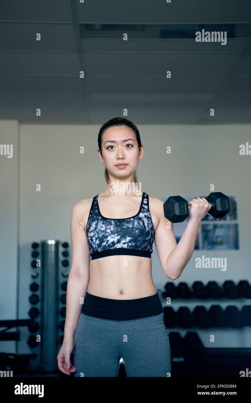 Femme faisant l'entraînement de force avec des haltères à la salle de gym Banque D'Images