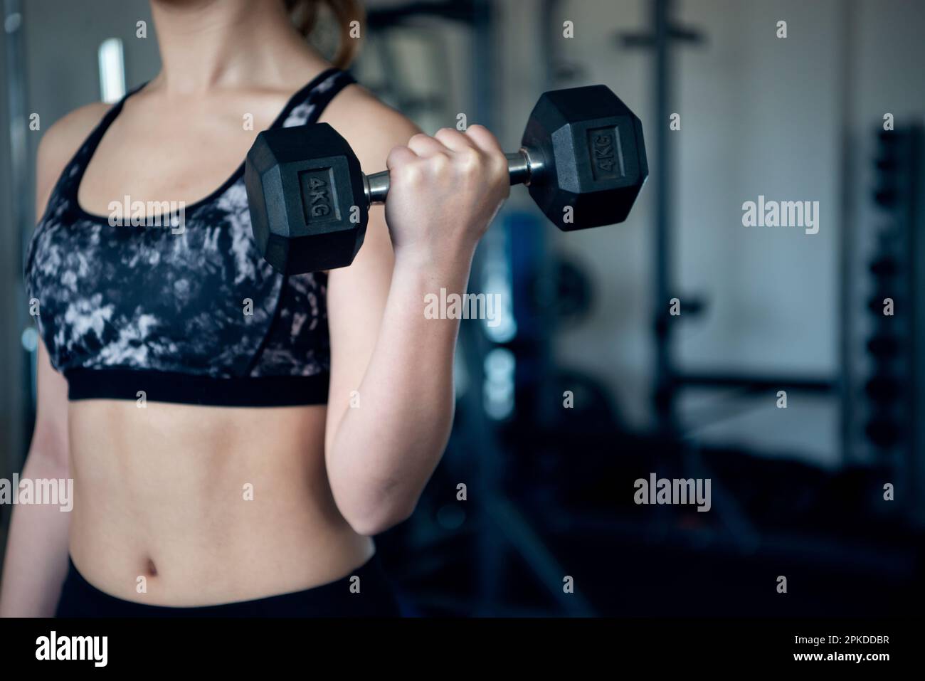 Femme faisant l'entraînement de force avec des haltères à la salle de gym Banque D'Images
