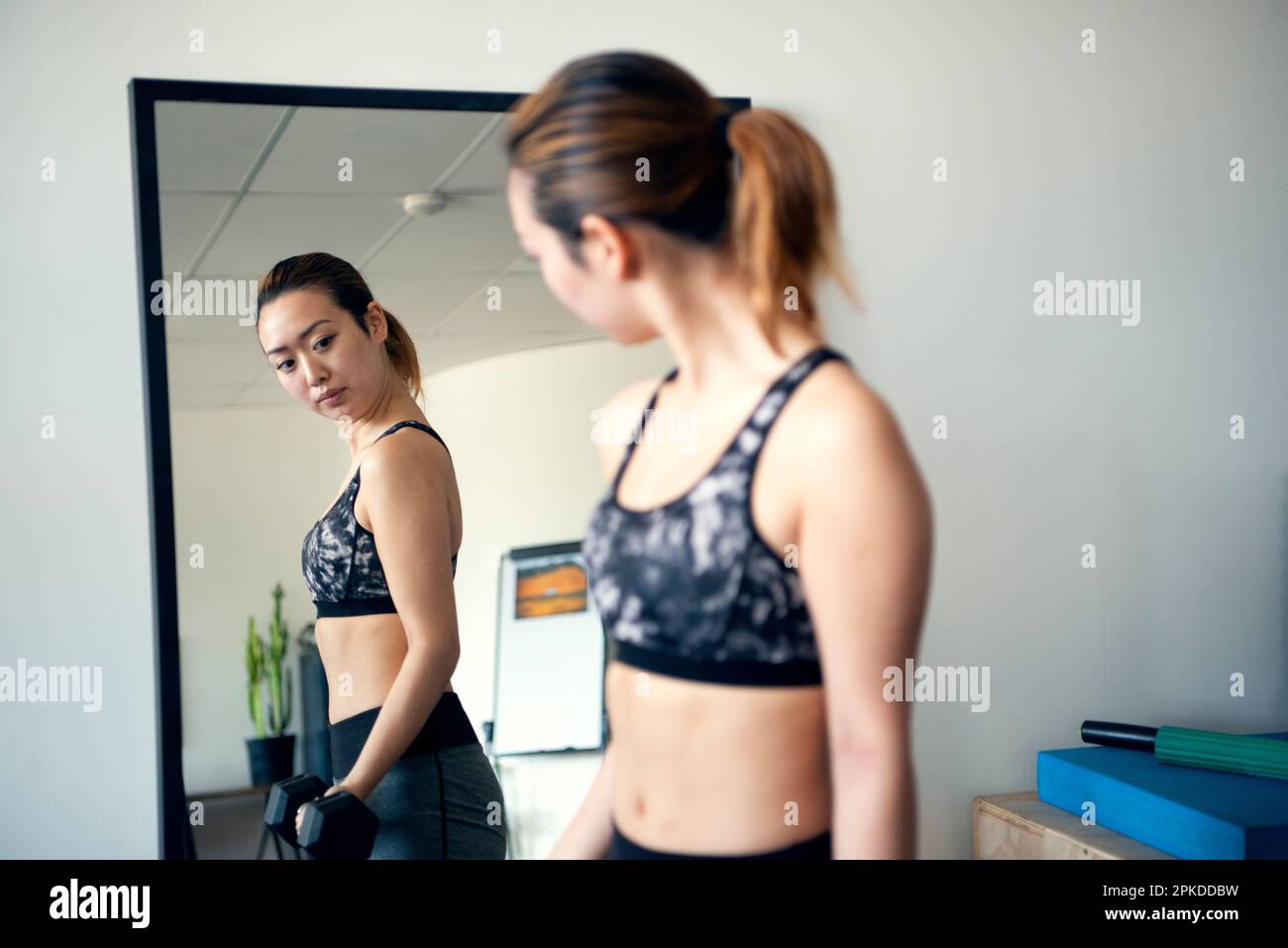 Femme faisant l'entraînement de force en regardant dans le miroir à la salle de gym Banque D'Images