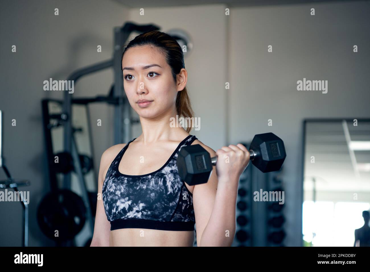 Femme faisant l'entraînement de force avec des haltères à la salle de gym Banque D'Images