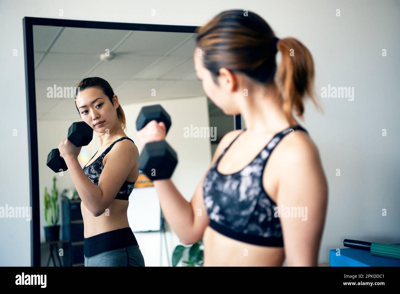 Femme faisant l'entraînement de force en regardant dans le miroir à la salle de gym Banque D'Images