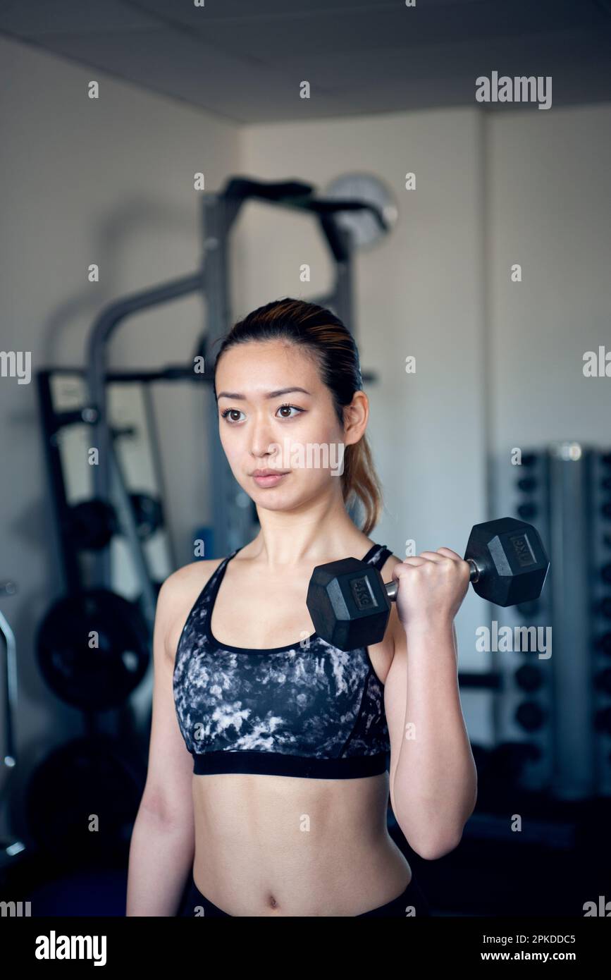Femme faisant l'entraînement de force avec des haltères à la salle de gym Banque D'Images