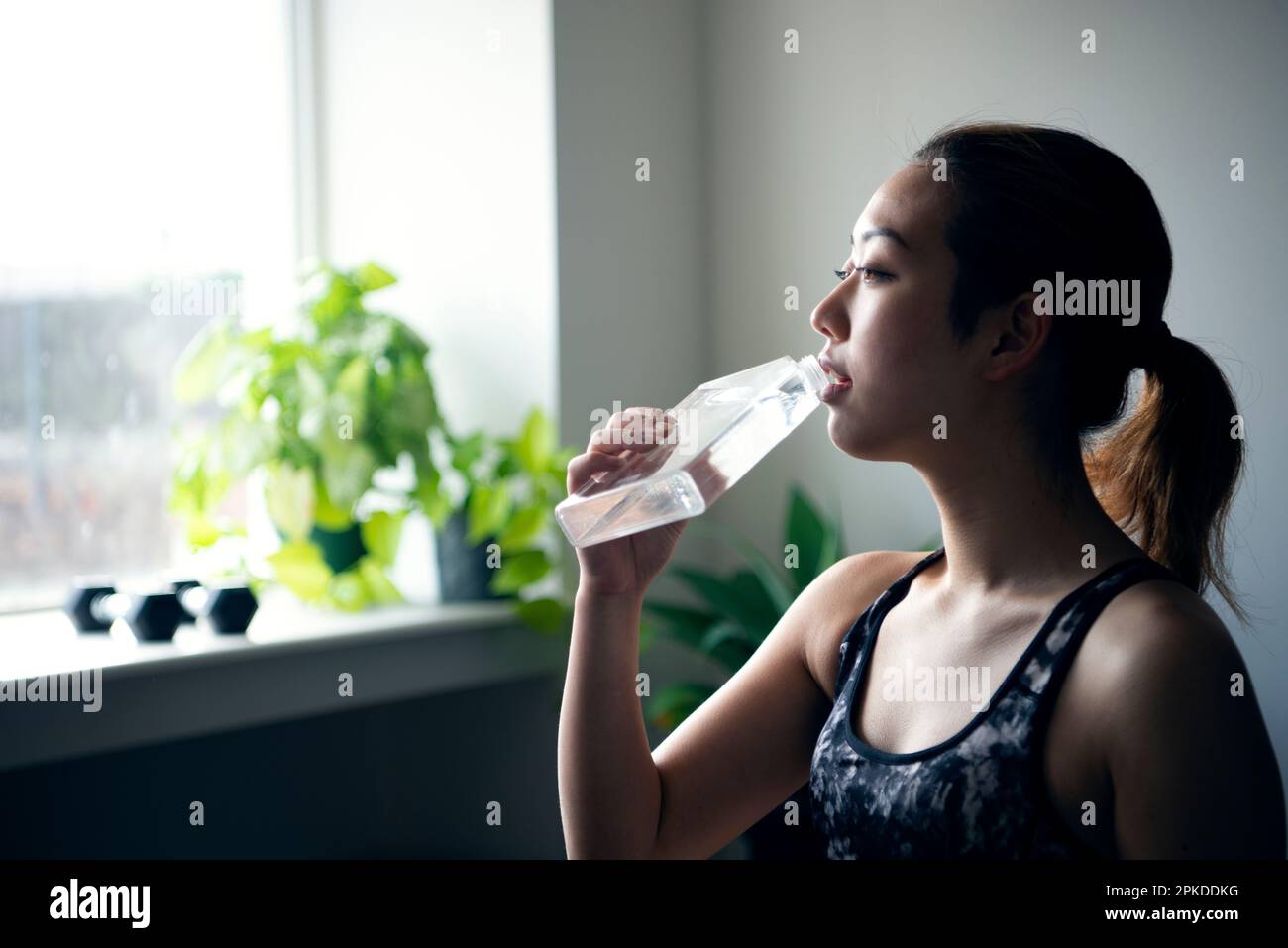 Une femme boit de l'eau dans une bouteille d'eau à la salle de gym Banque D'Images