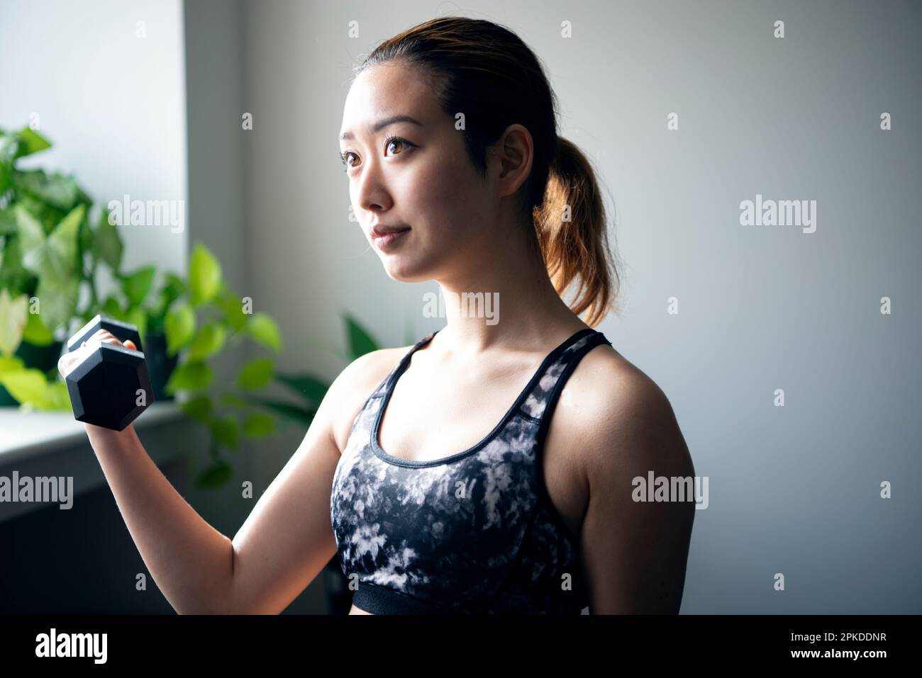 Femme faisant l'entraînement de force avec des haltères à la salle de gym Banque D'Images