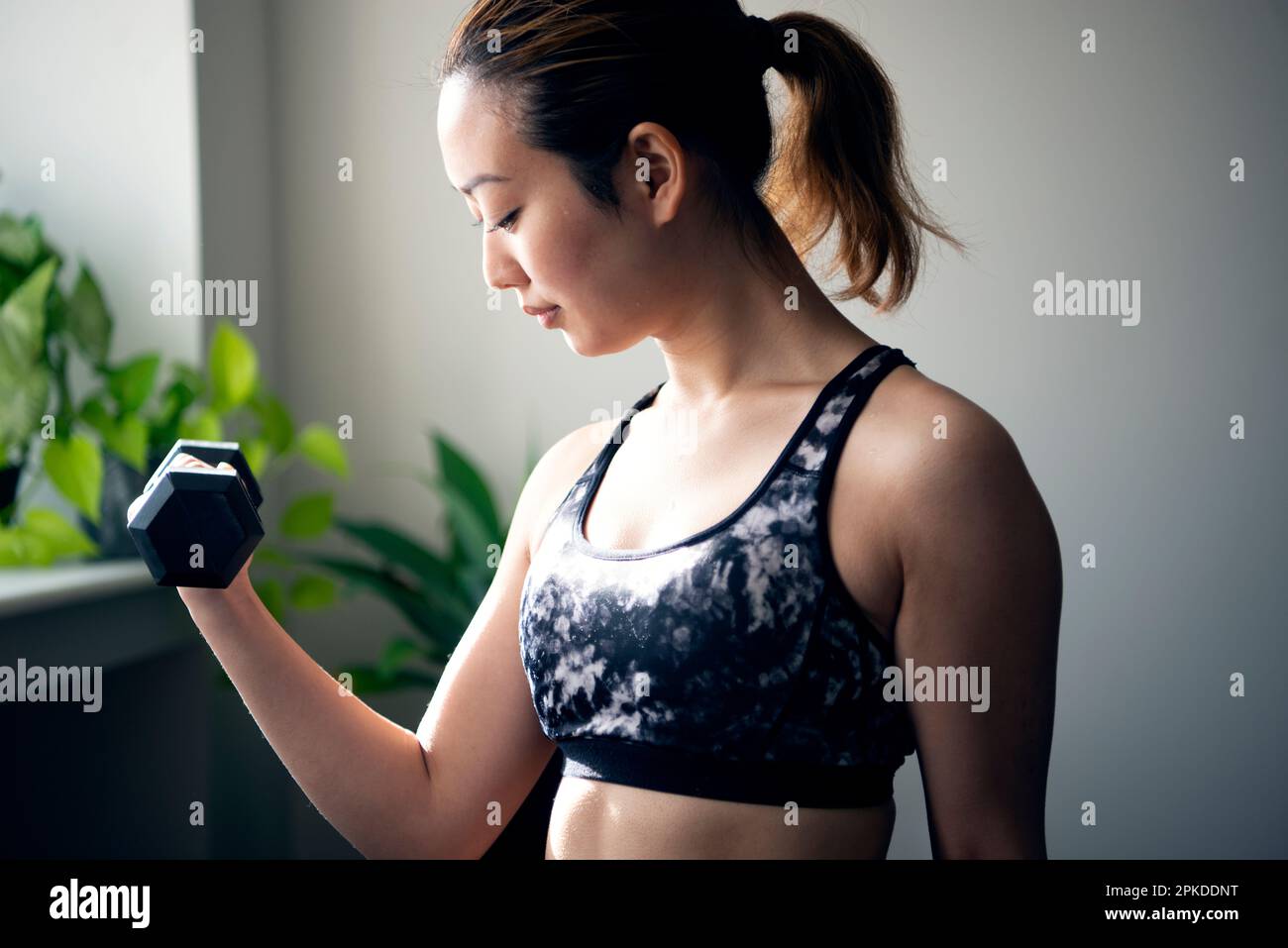 Femme faisant l'entraînement de force avec des haltères à la salle de gym Banque D'Images