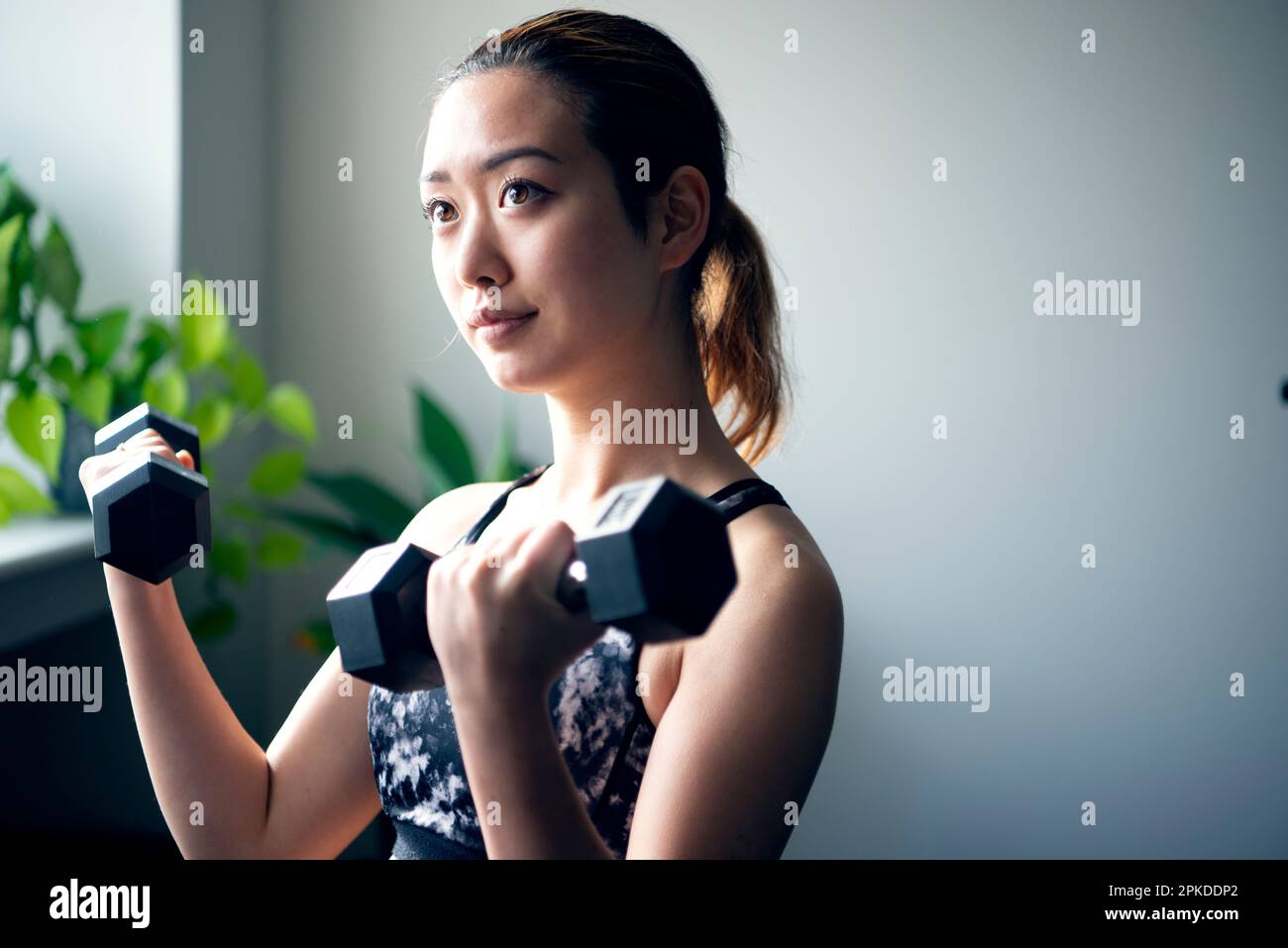 Femme faisant l'entraînement de force avec des haltères à la salle de gym Banque D'Images