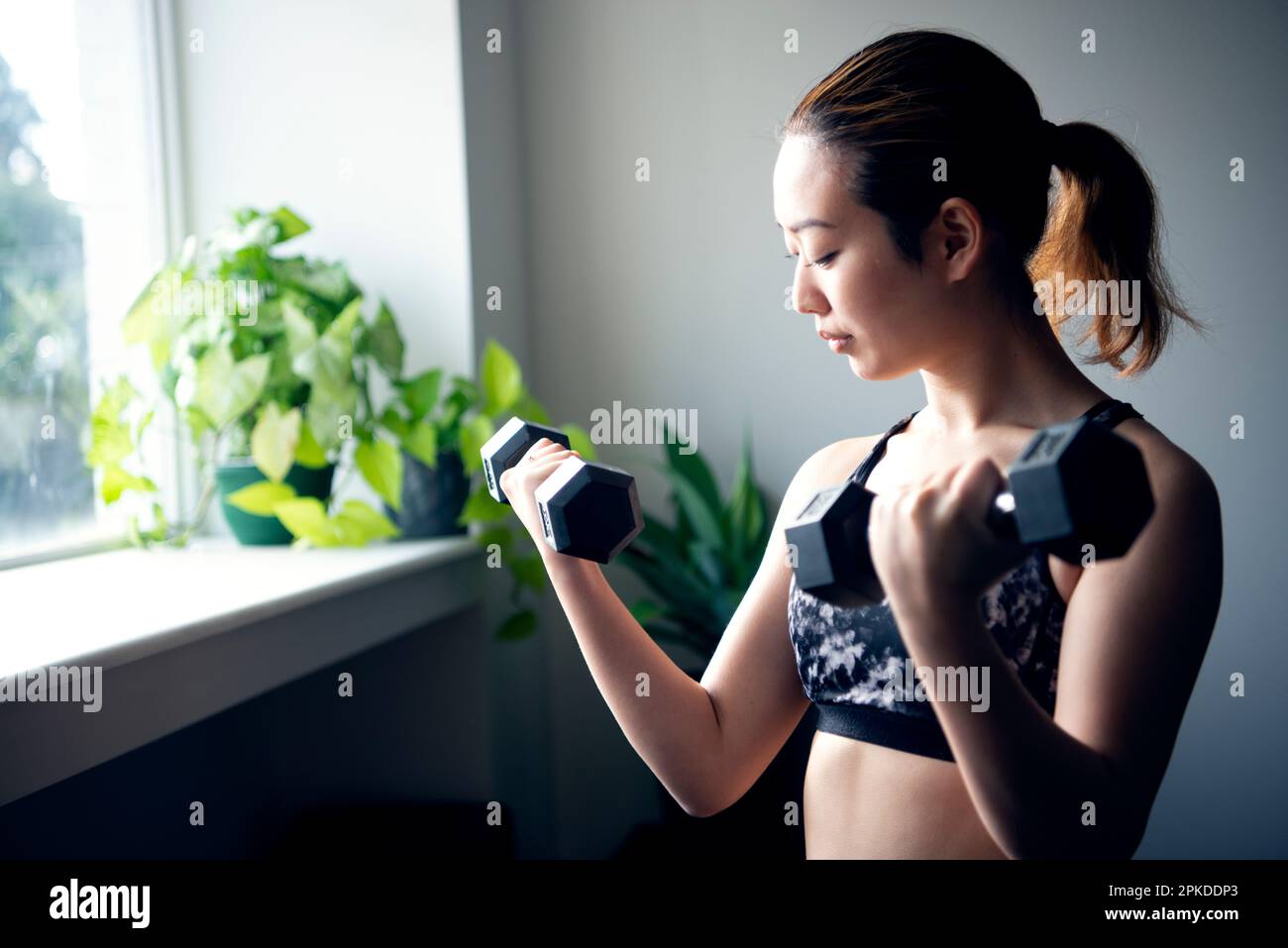 Femme faisant l'entraînement de force avec des haltères à la salle de gym Banque D'Images