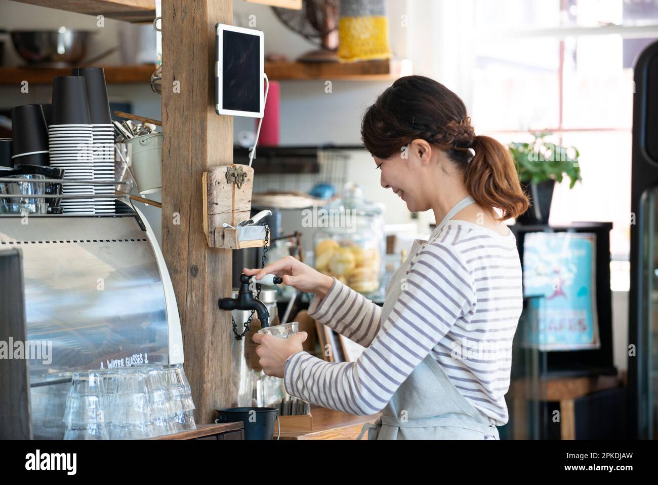 Une serveuse souriante qui se sert de l'eau dans un café Banque D'Images