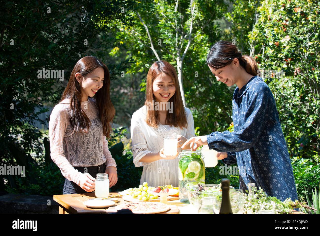 Trois femmes souriantes appréciant une fête dans le jardin Banque D'Images