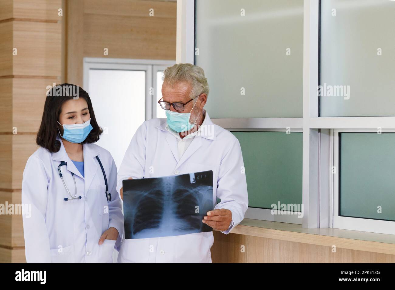 expertise chirurgicale senior regardant le film radiographique pour donner des conseils et discuter pour le traitement chirurgical le patient avec une jeune femme asiatique médecin à hospita Banque D'Images
