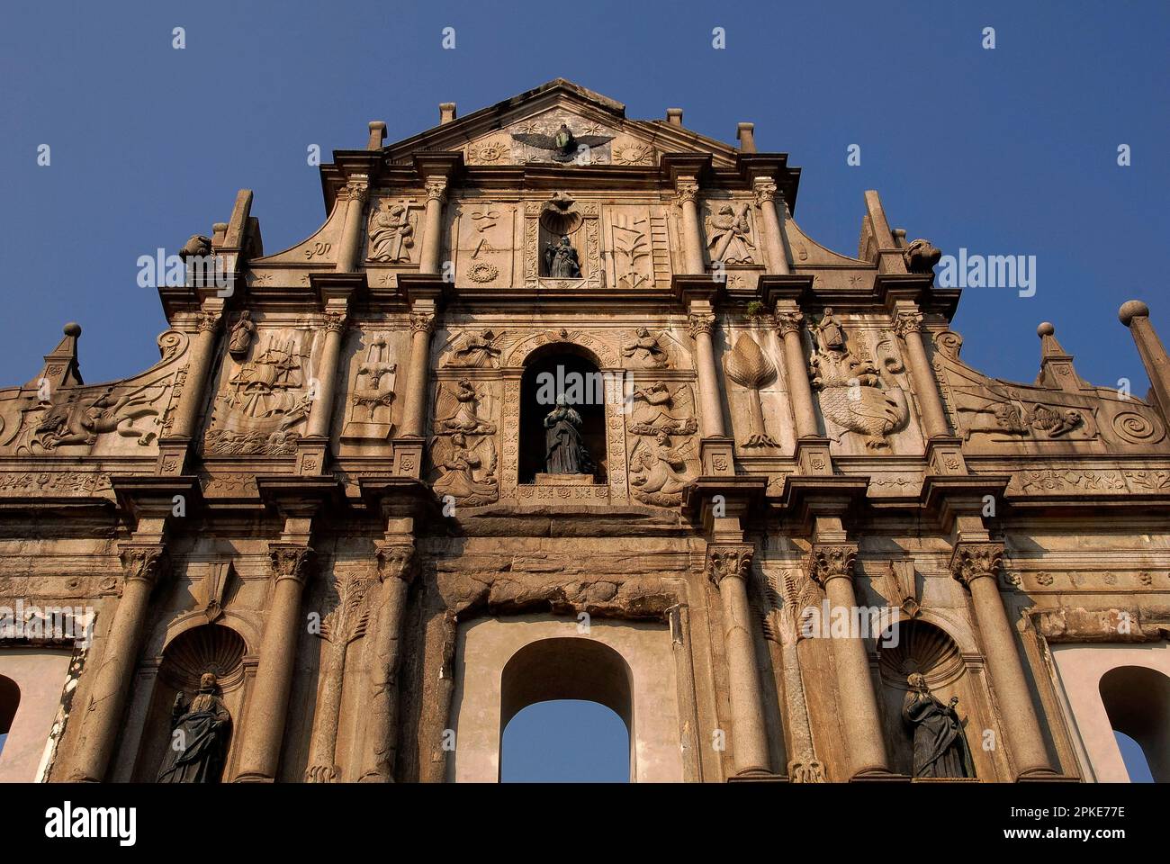 Le mélange unique et bizarre de l'art colonial chinois, catholique jésuite et portugais sur la façade en granit de l'église Saint-Paul de Macao, en Chine, en ruines de 1620s, comprend Sainte-Marie qui piétinent une hydre à sept têtes, un diable hideeux et un squelette humain, avec des flèches, un galléon, une foule céleste d'anges et de palmiers. Banque D'Images