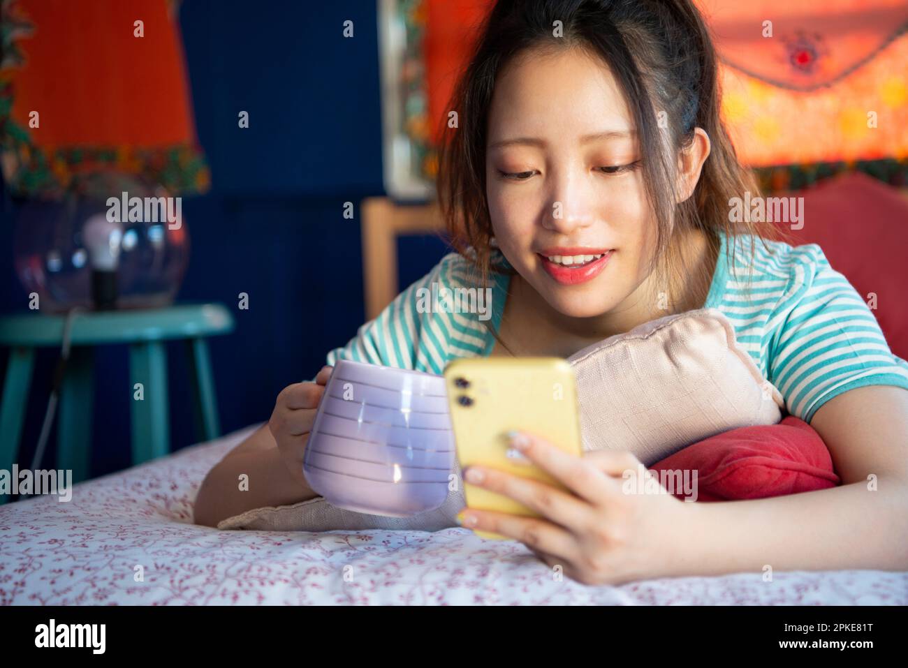 Femme touchant son téléphone sur le lit Banque D'Images
