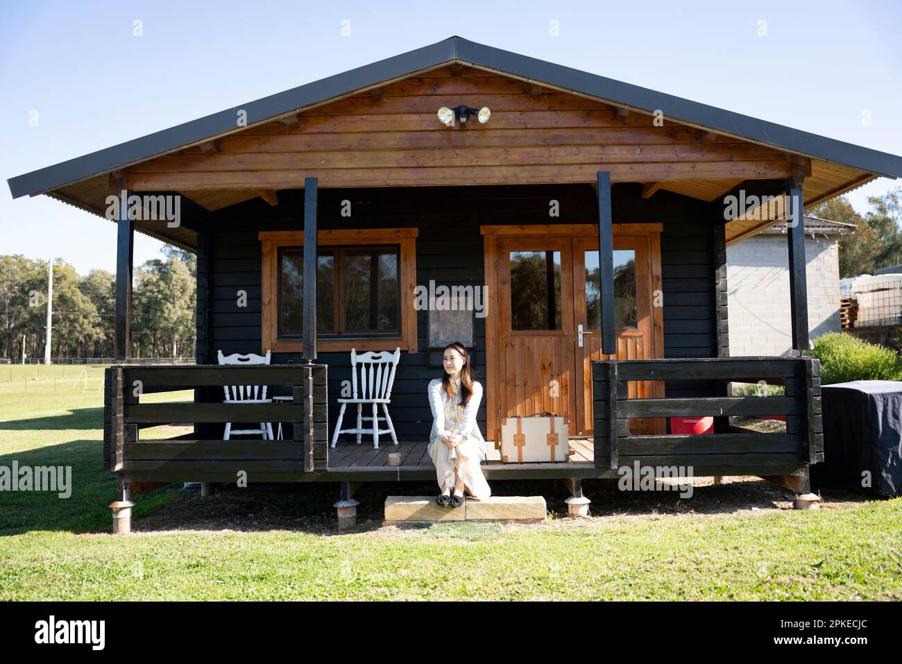 Femme se reposant sur le porche du cottage Banque D'Images