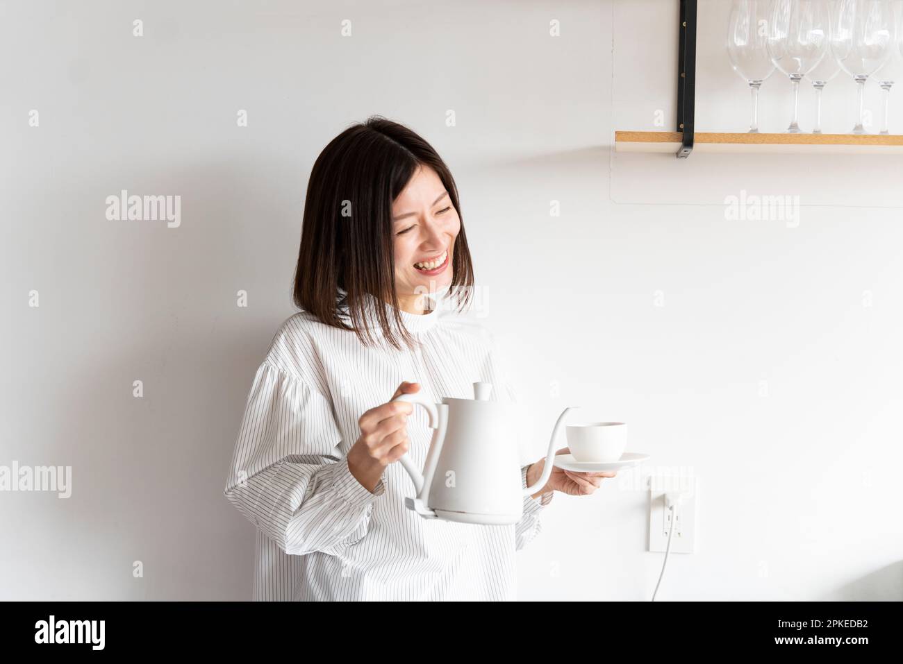 Femme riant avec une bouilloire électrique et une tasse Banque D'Images