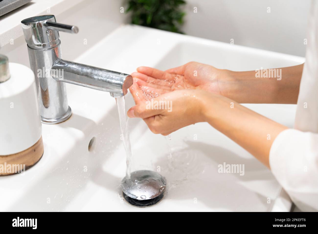 Main de femme recevant de l'eau d'un robinet Banque D'Images