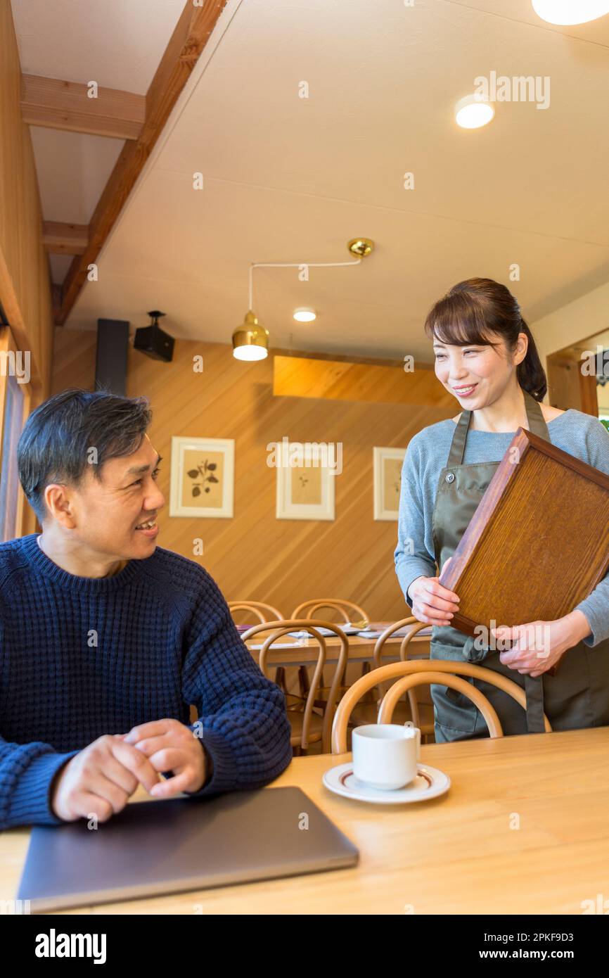 Serveuse servant du café à un client masculin Banque D'Images