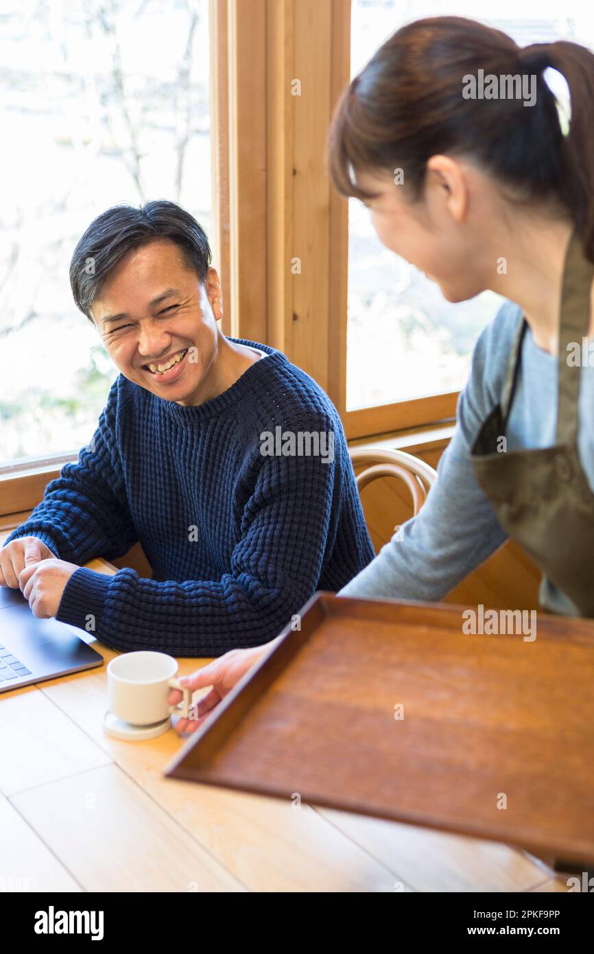 Serveuse servant du café à un client masculin Banque D'Images