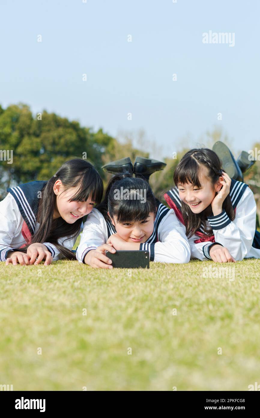 Écolière couché sur l'herbe prenant une photo Banque D'Images