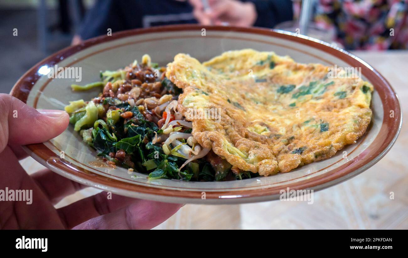 Nasi Pecel, menu traditionnel javanais avec sauce épicée aux arachides, légumes durs et œuf frit pour le petit-déjeuner ou le déjeuner Banque D'Images