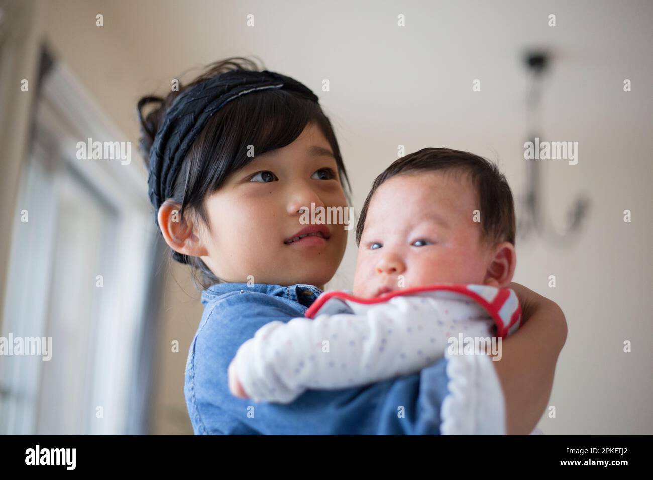 Une fille de l'école élémentaire tenant son petit frère Banque D'Images