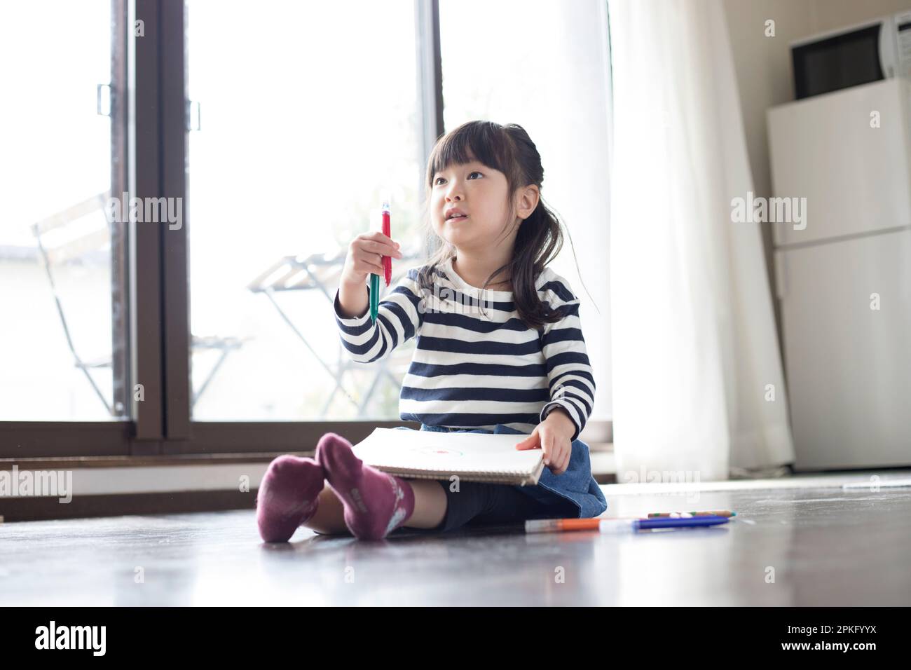 Fille assise sur le sol dessin dans un carnet de croquis Banque D'Images