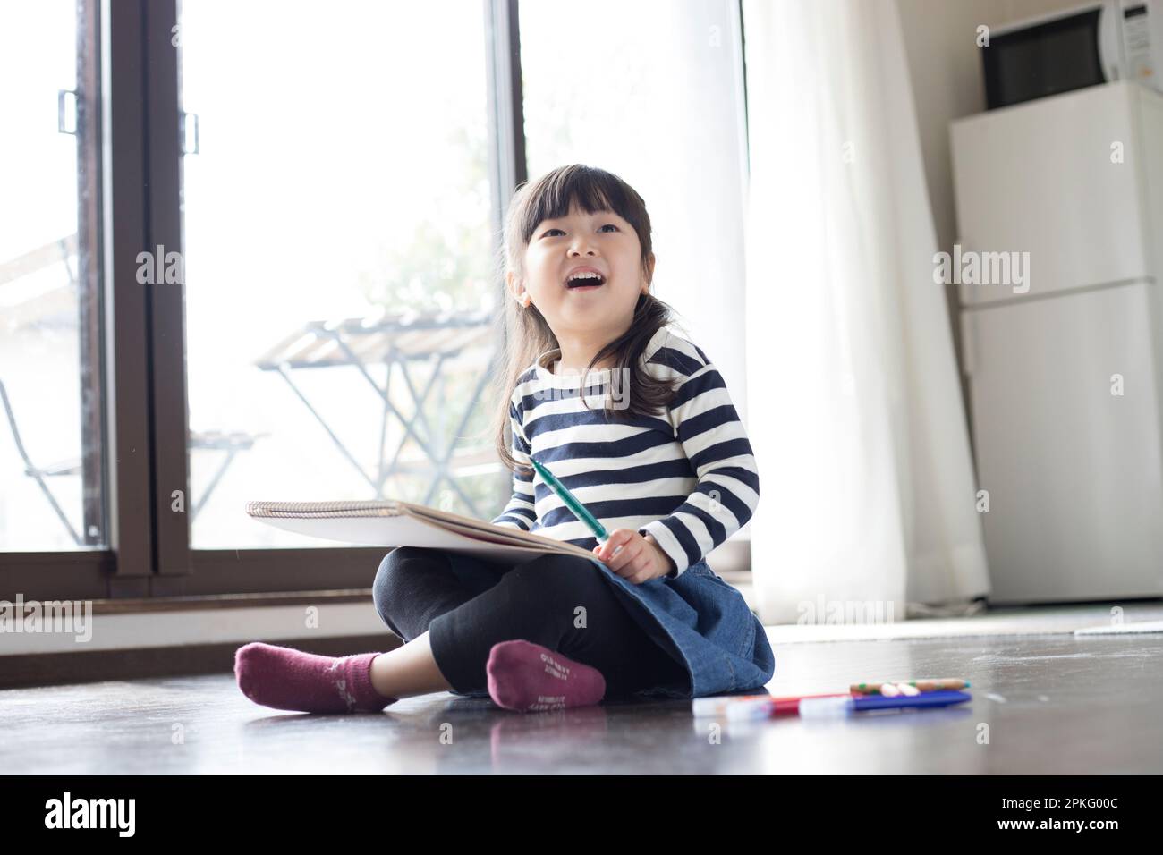 Fille assise sur le sol dessin dans son carnet de croquis Banque D'Images