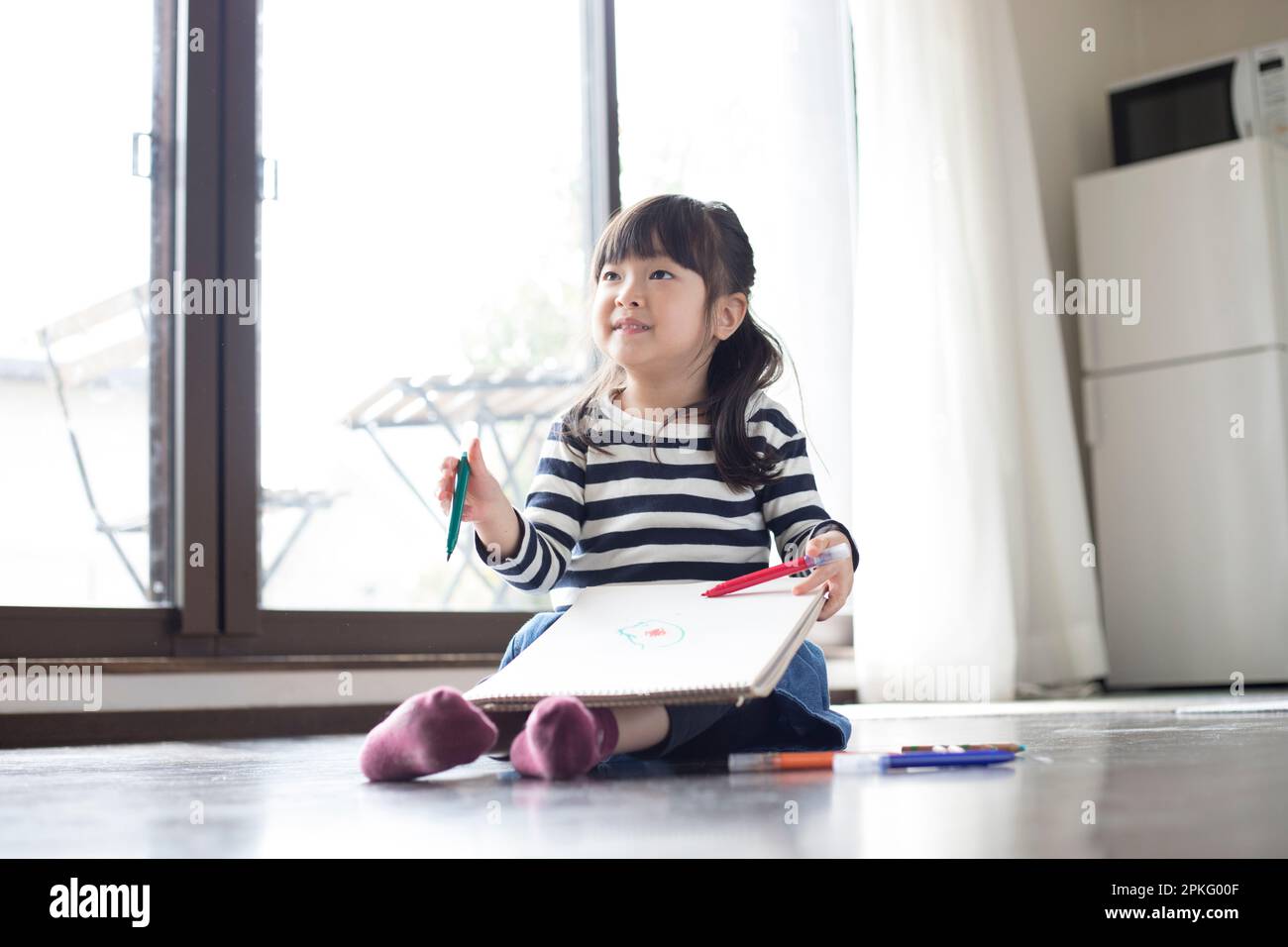 Fille assise sur le sol dessin dans son carnet de croquis Banque D'Images