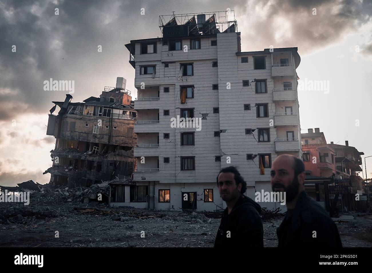 Hatay, Turquie. 07th avril 2023. Dans une zone où les débris ont été enlevés, des personnes et des bâtiments endommagés attendant d'être démolis derrière ont été vus. Il y a 2 mois depuis le tremblement de terre de 6 février 2023. Dans le district de Harbiye, dans le district de Defne, à Hatay, les victimes du tremblement de terre tentent de retrouver une vie normale. Crédit : SOPA Images Limited/Alamy Live News Banque D'Images