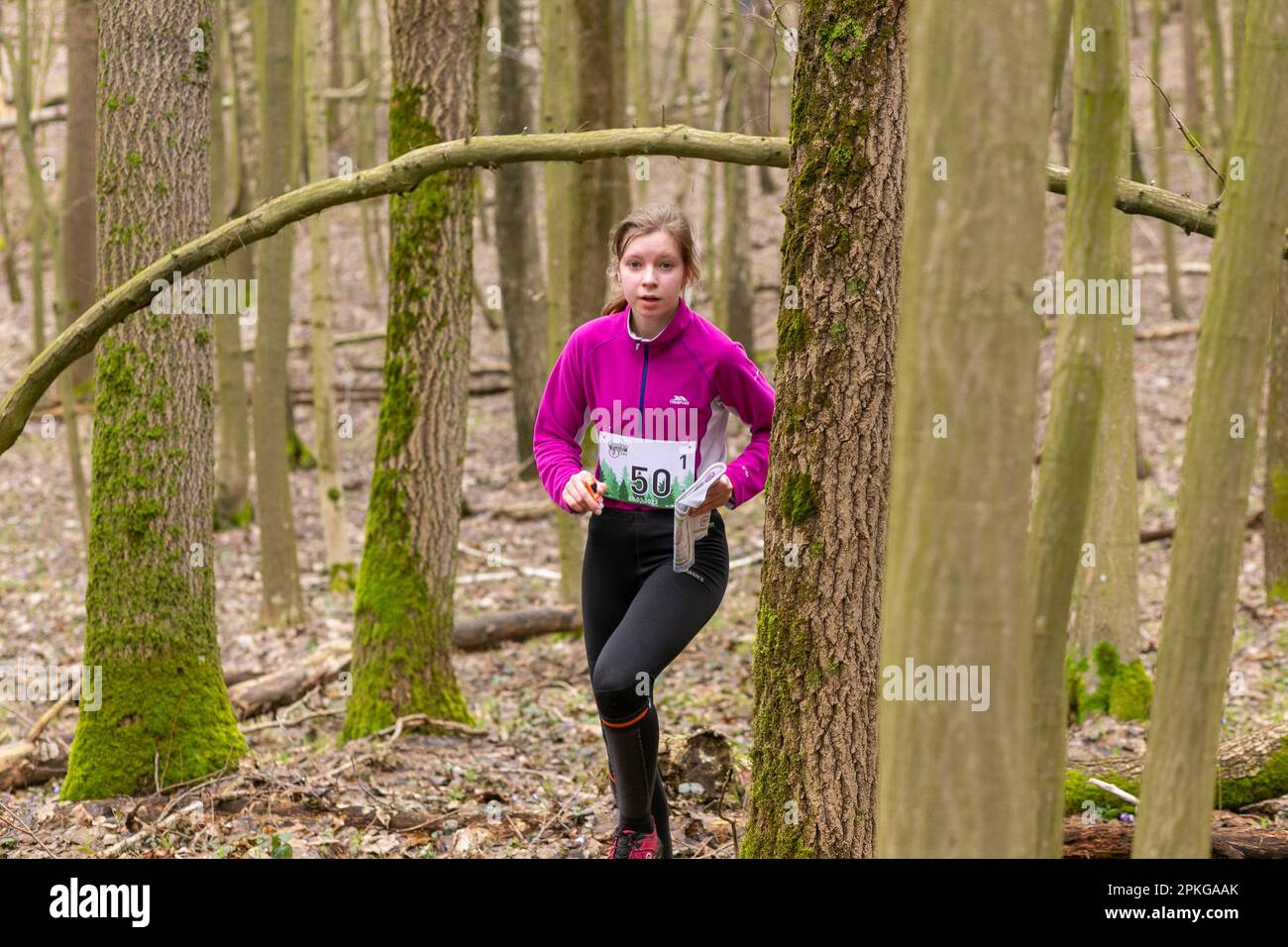 Grodno, Bélarus - 26 mars 2023 : une jeune fille adorable portant des vêtements de sport traversant une forêt pendant un exercice dans la forêt de Grodno Banque D'Images