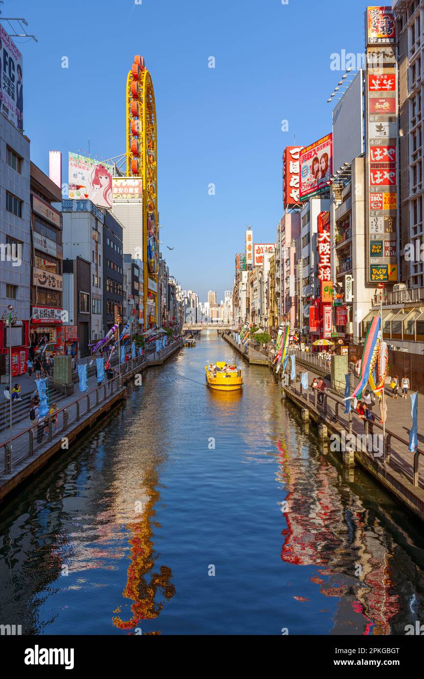 OSAKA, JAPON - 3 MAI 2014 : un bateau passe sur le canal sous les célèbres publicités du canal de Dotonbori. Banque D'Images
