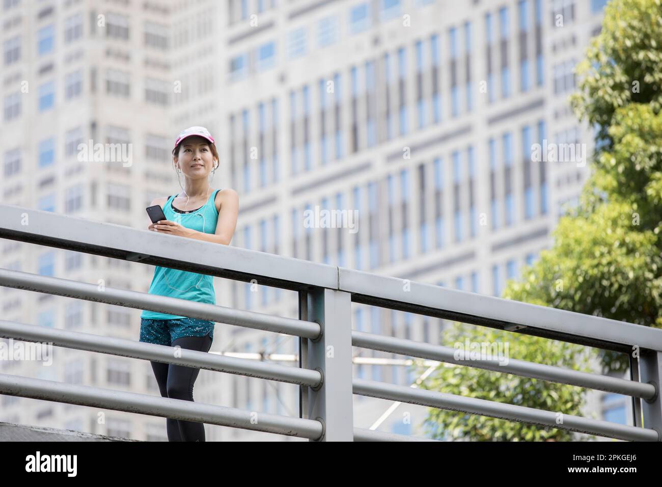 Une femme qui fait du jogging regarde son téléphone devant une tour Banque D'Images