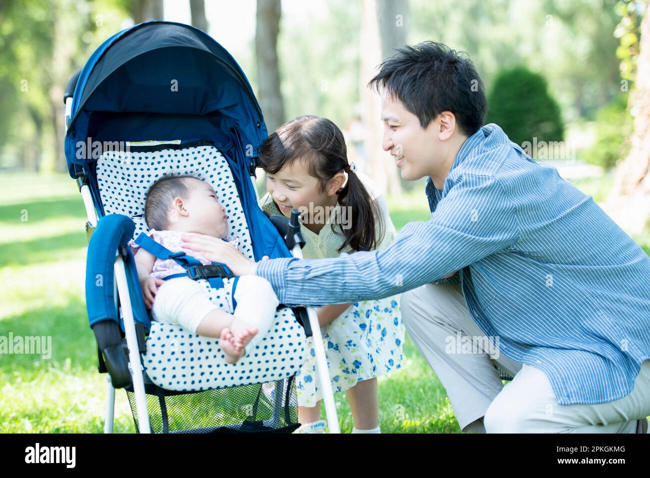 Parents et enfants regardant bébé dans la poussette Banque D'Images