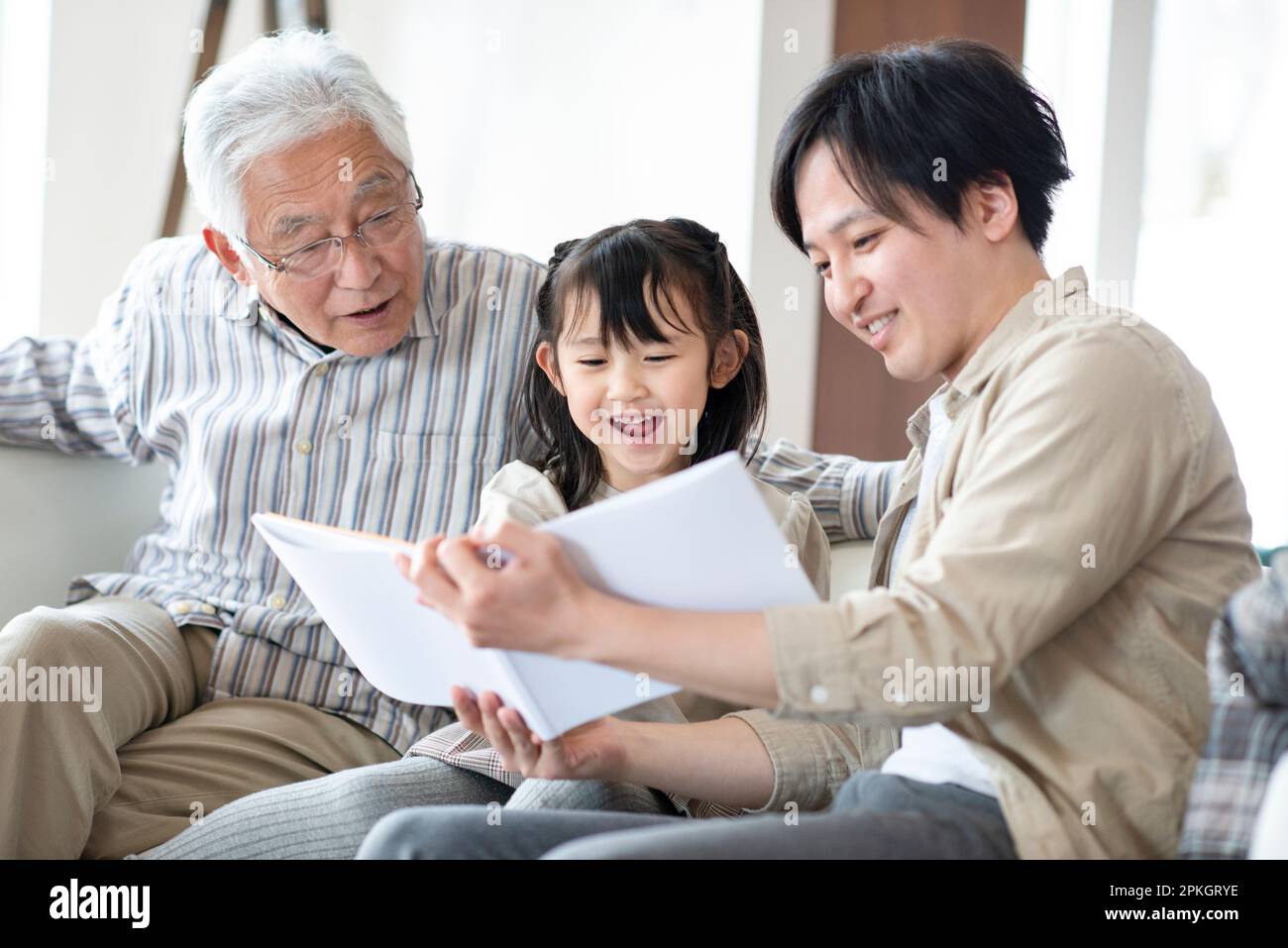 Famille de 3 générations lisant un livre d'images Banque D'Images