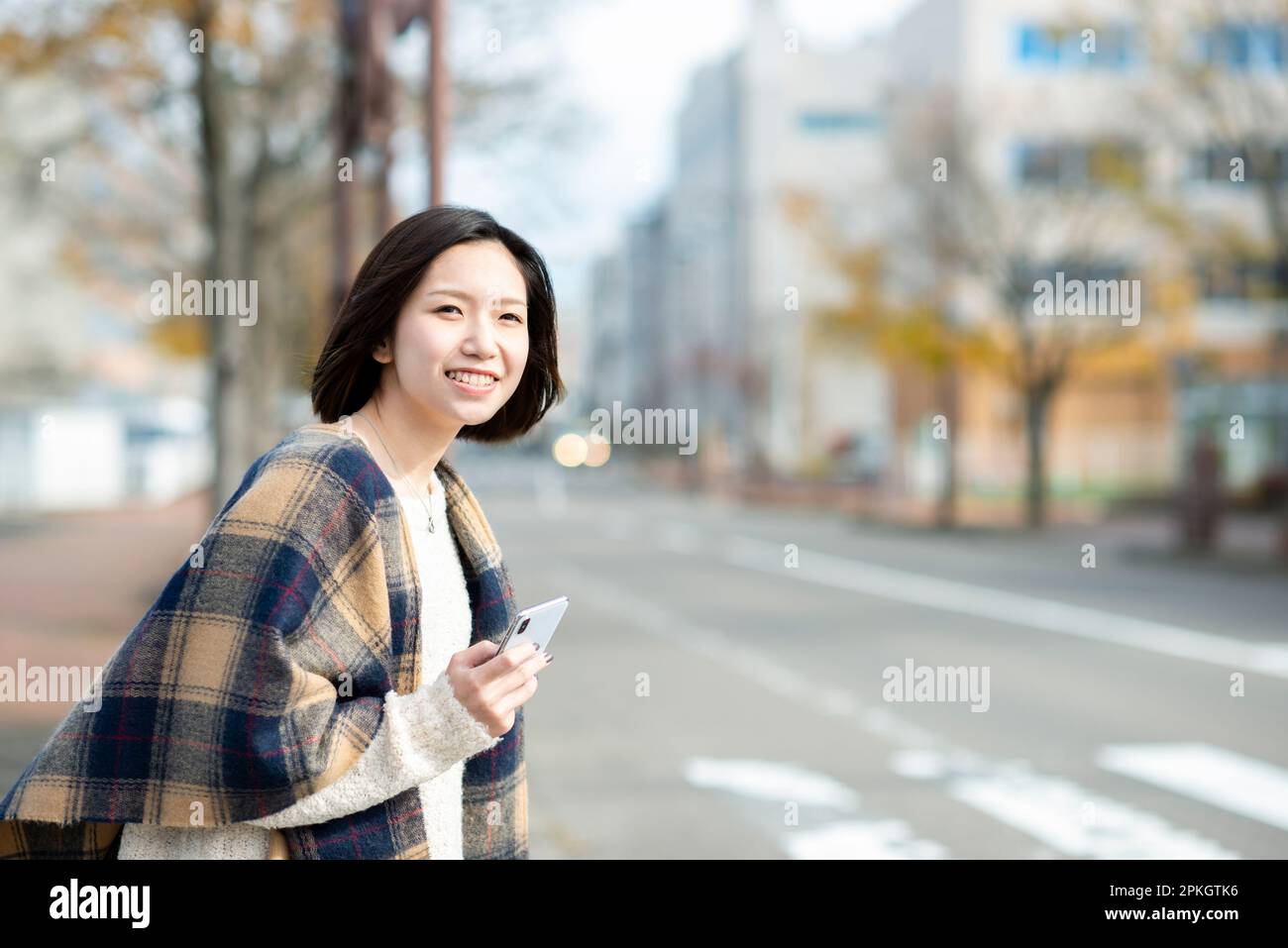 Femme en attente d'un taxi à l'aide d'une application Dispatch Banque D'Images