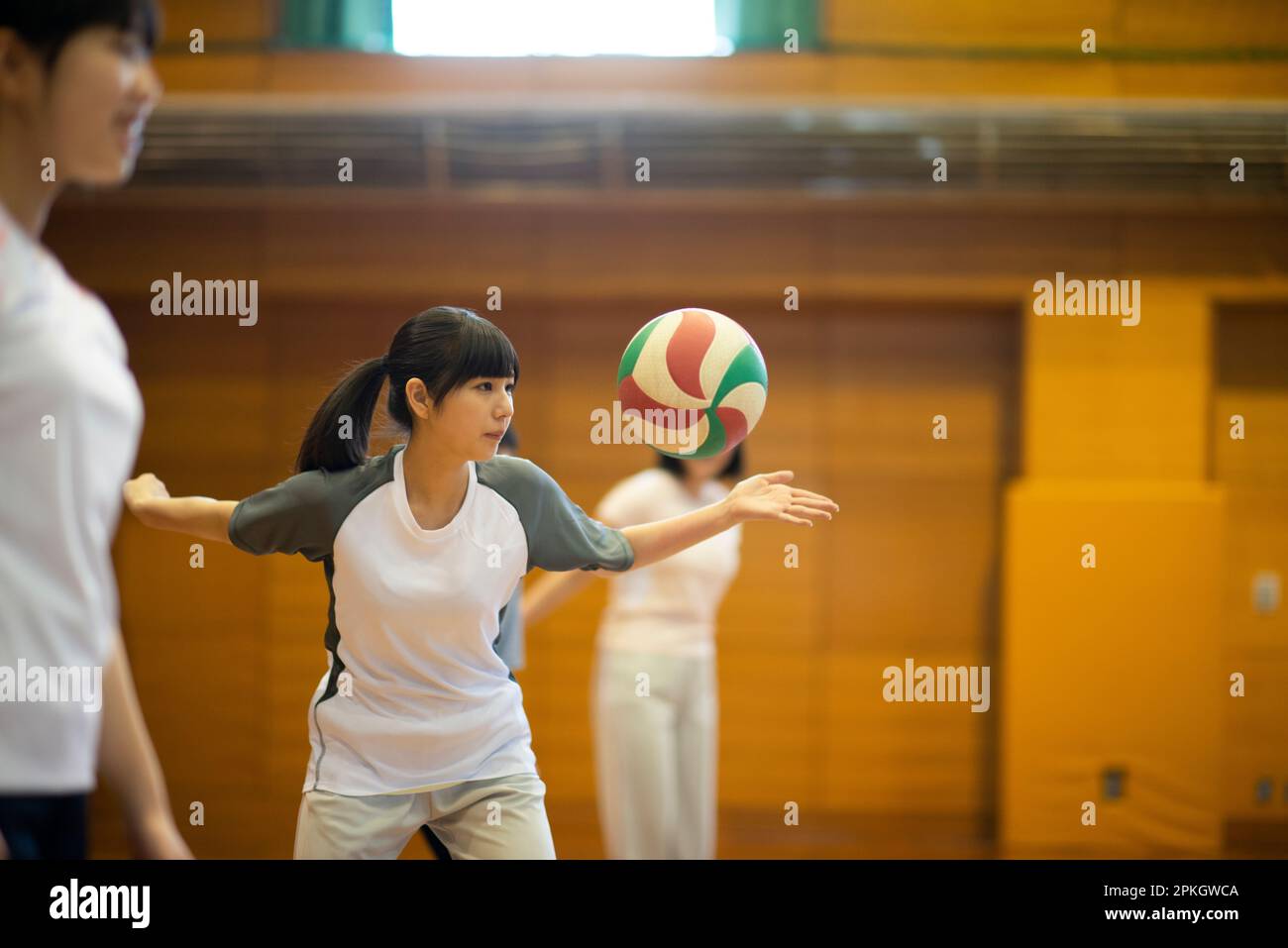 Étudiants pratiquant le volley-ball dans la salle de sport Banque D'Images