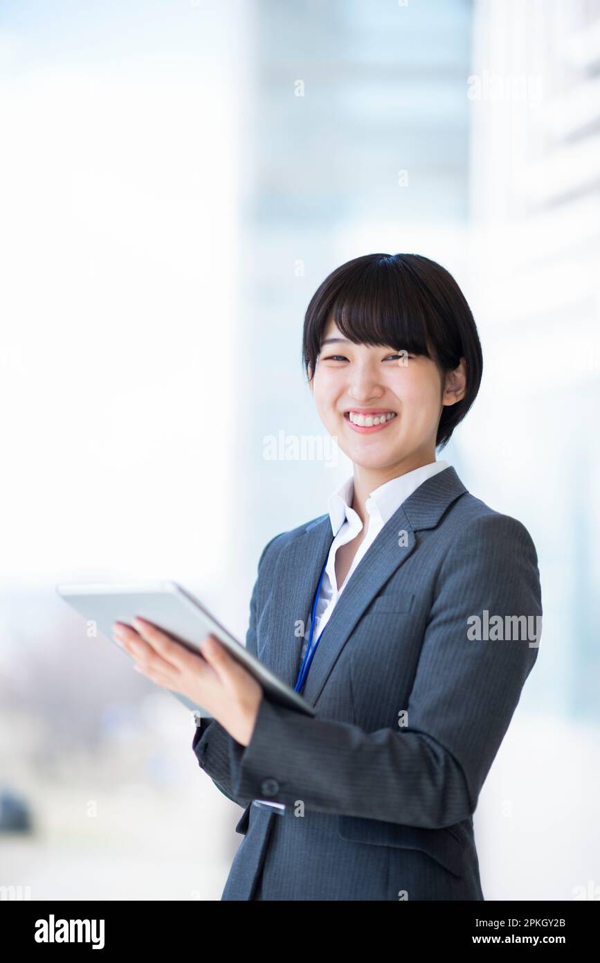 Femme d'affaires tenant et souriant devant un Tablet PC Banque D'Images