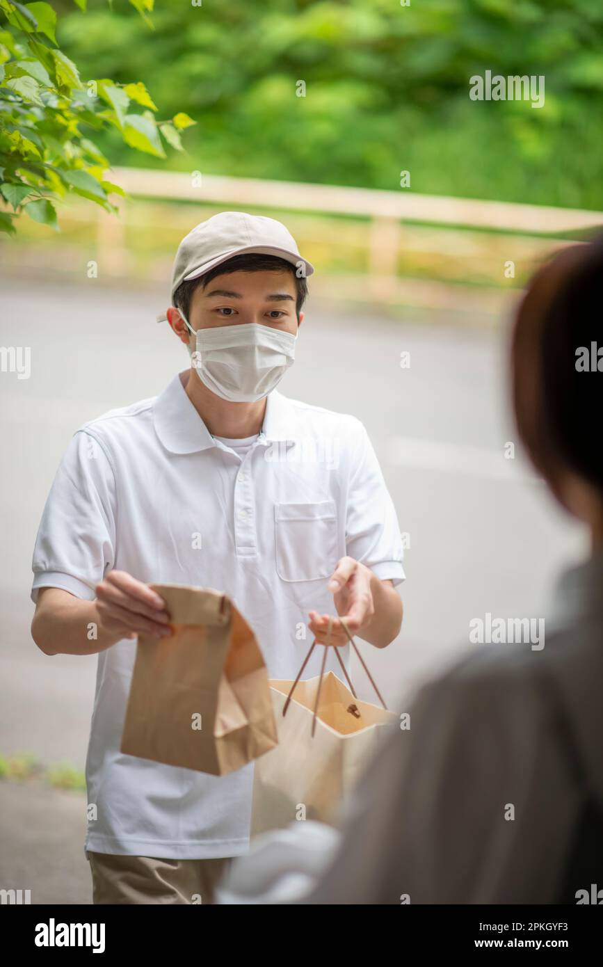 Livreur qui remet un sac en papier à la porte avant Banque D'Images