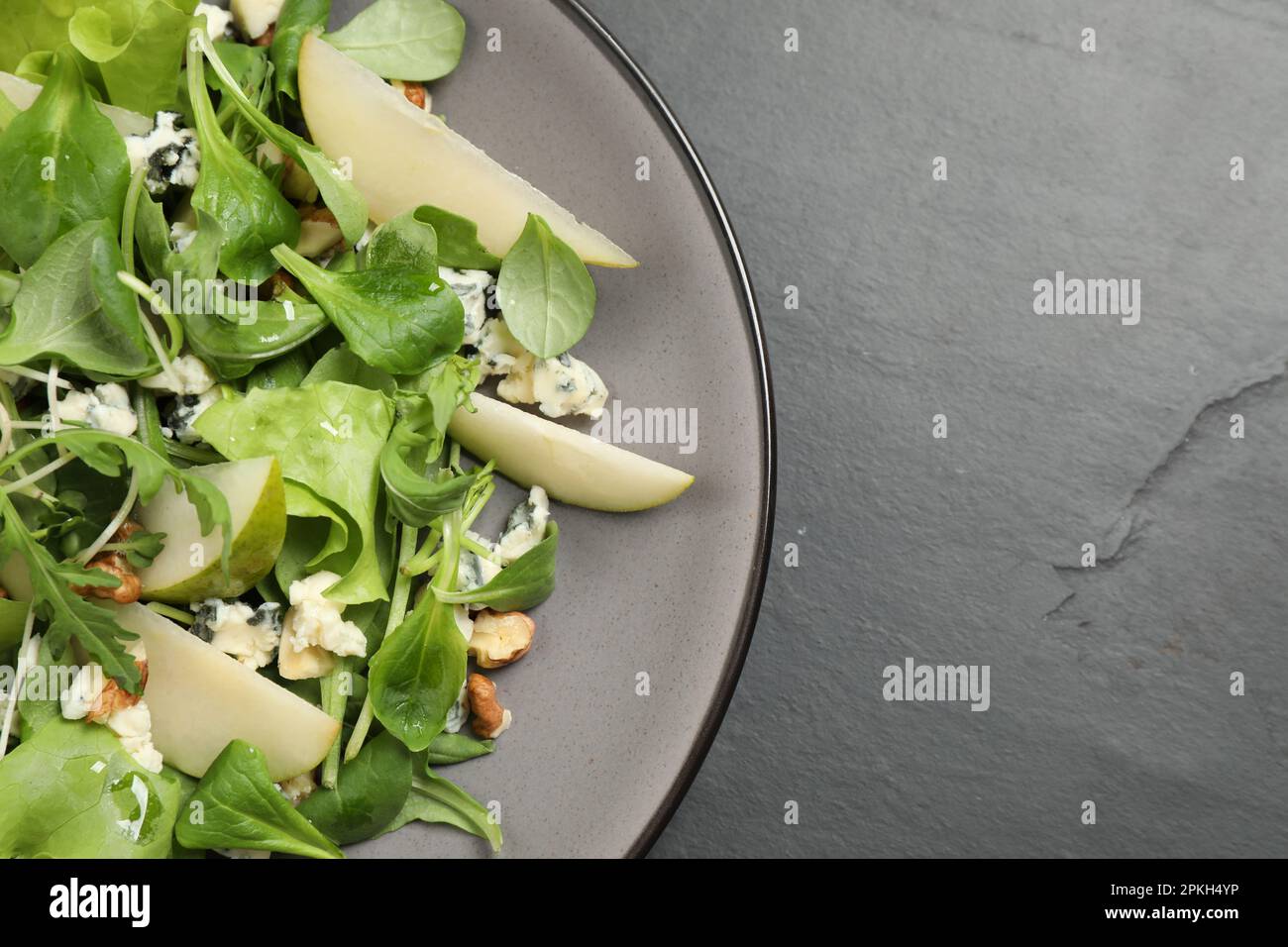 Salade savoureuse avec tranches de poire sur table noire, vue du dessus. Espace pour le texte Banque D'Images