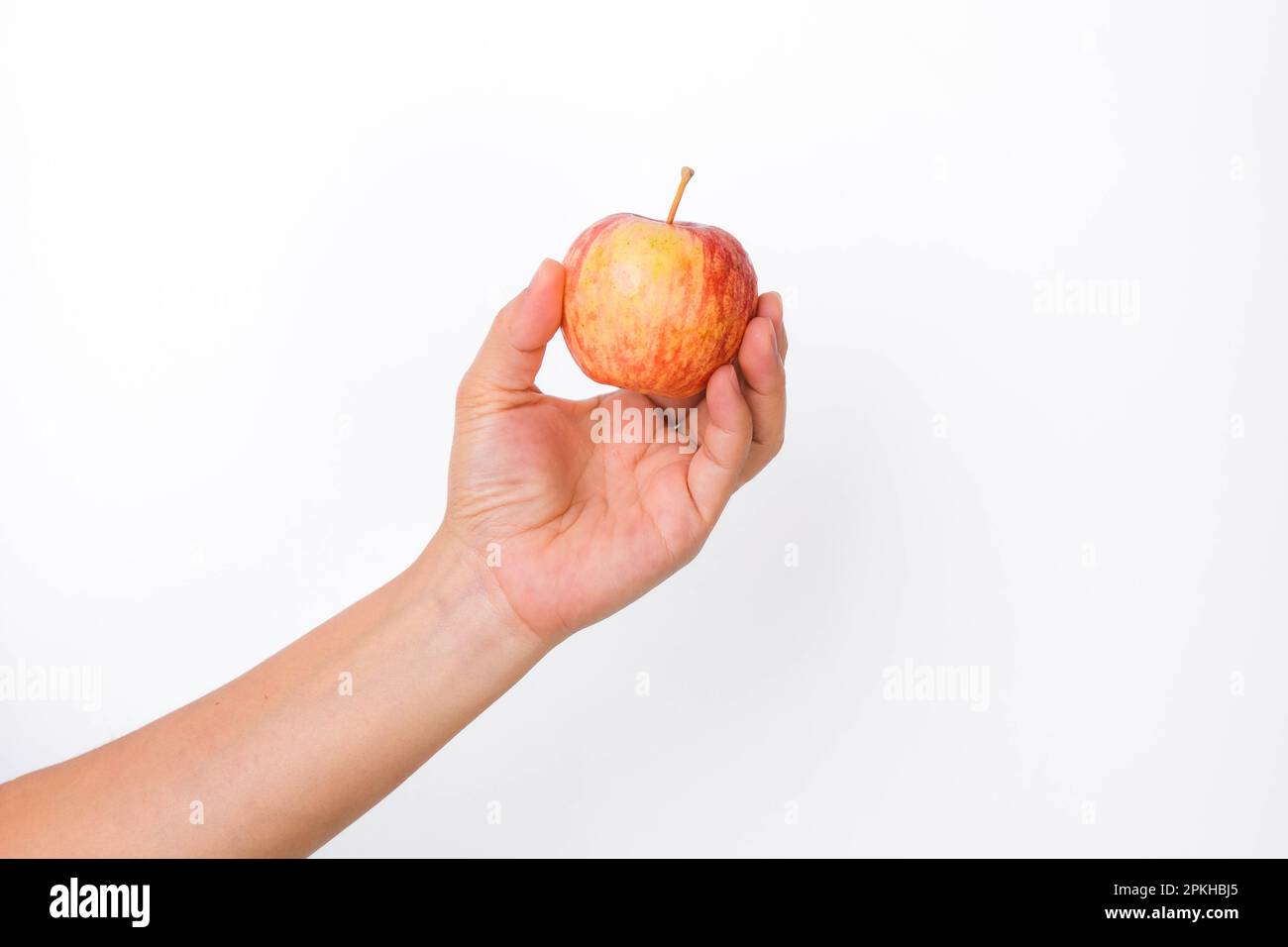Main tenant la pomme rouge isolée sur fond blanc. Pomme rouge mûre dans la main humaine. Banque D'Images