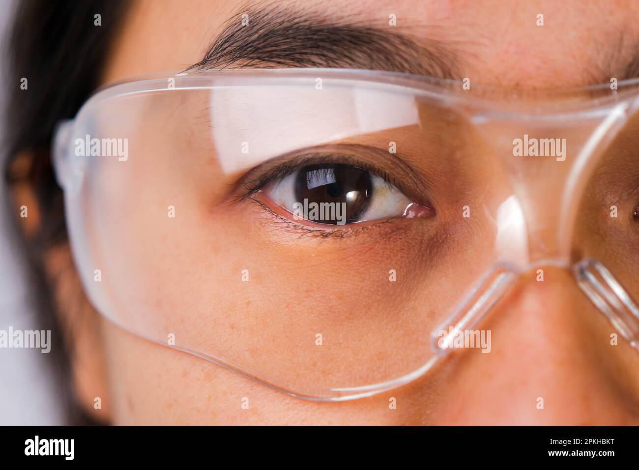 Gros plan de l'œil de la femme portant des lunettes de sécurité transparentes. Femme asiatique portant des lunettes de protection. Banque D'Images