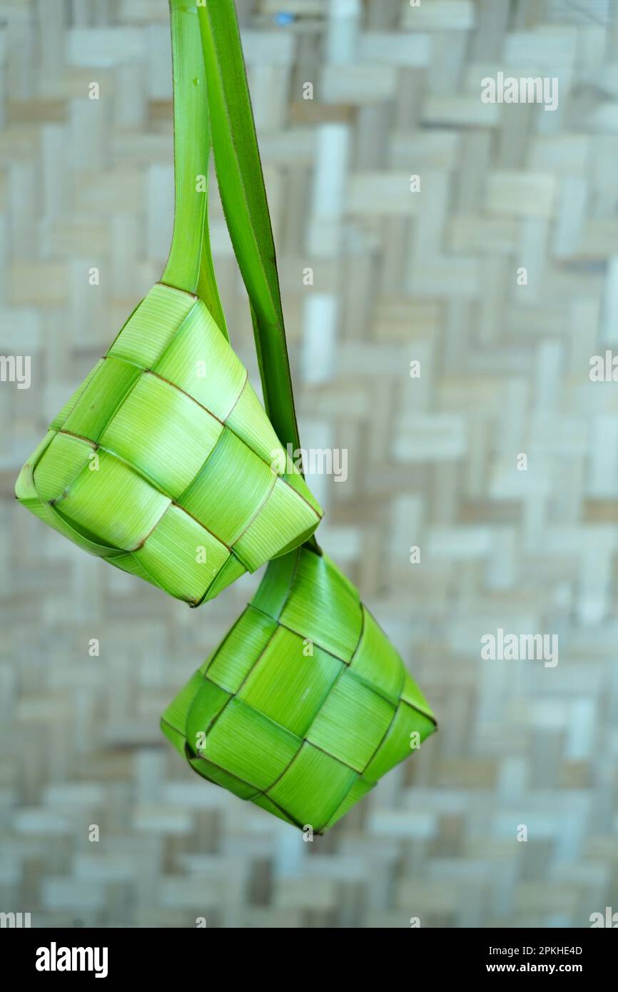 Ketupas vide ou feuille de palmier tissée vide accrochée dans une pièce avec fond de mur en bambou tissé. Préparation à l'Idul Fitri ou à l'Eid Mubarak en Indonésie. Copier Banque D'Images