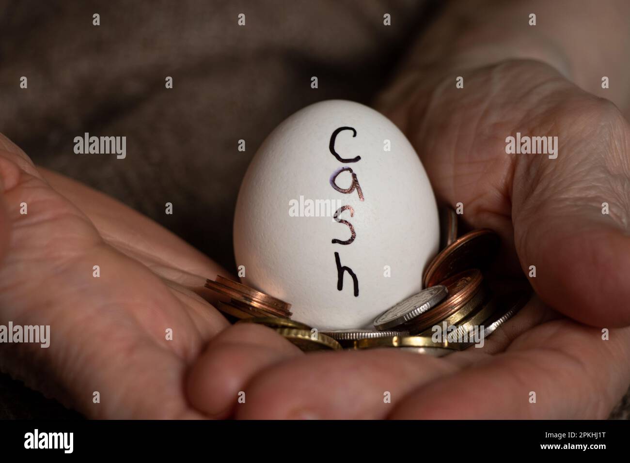 Un œuf avec l'inscription argent et pièces dans les mains d'une grand-mère, argent Banque D'Images