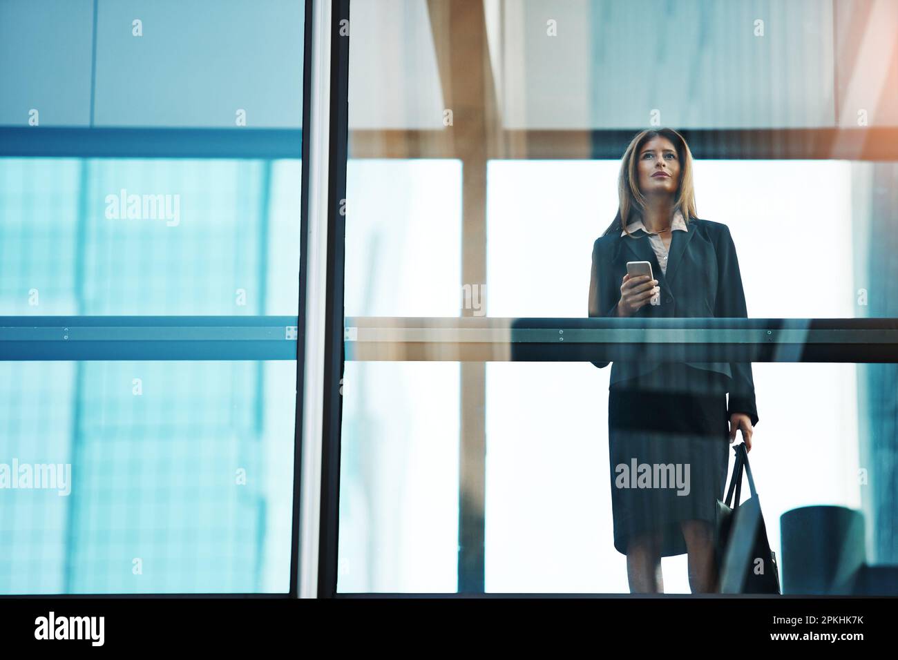 Faites-le jusqu'au sommet, restez au sommet. une femme d'affaires utilisant un téléphone mobile dans un bureau moderne en verre. Banque D'Images