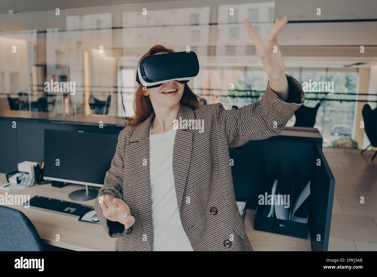 Employée de bureau utilisant la réalité virtuelle pour visualiser et parcourir les fichiers de projet, utilisant ses mains pour contrôler les objets dans le monde numérique, les affaires enthousiastes Banque D'Images