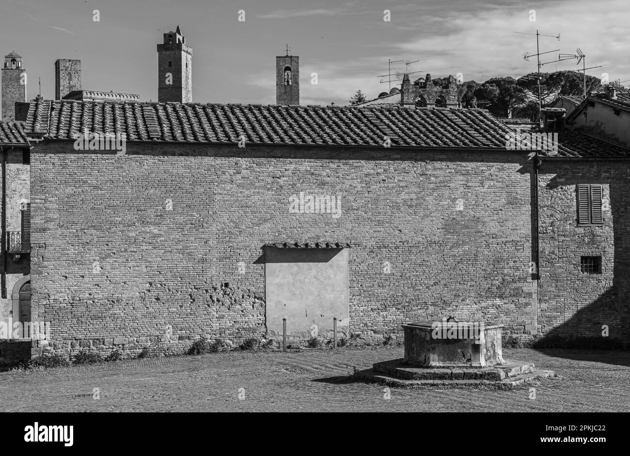 La citerne centrale de la place Saint-Augustin et l'église Saint-Augustin, une église la plus importante à San Gimignano, province de Sienne, région Toscane, Italie Banque D'Images