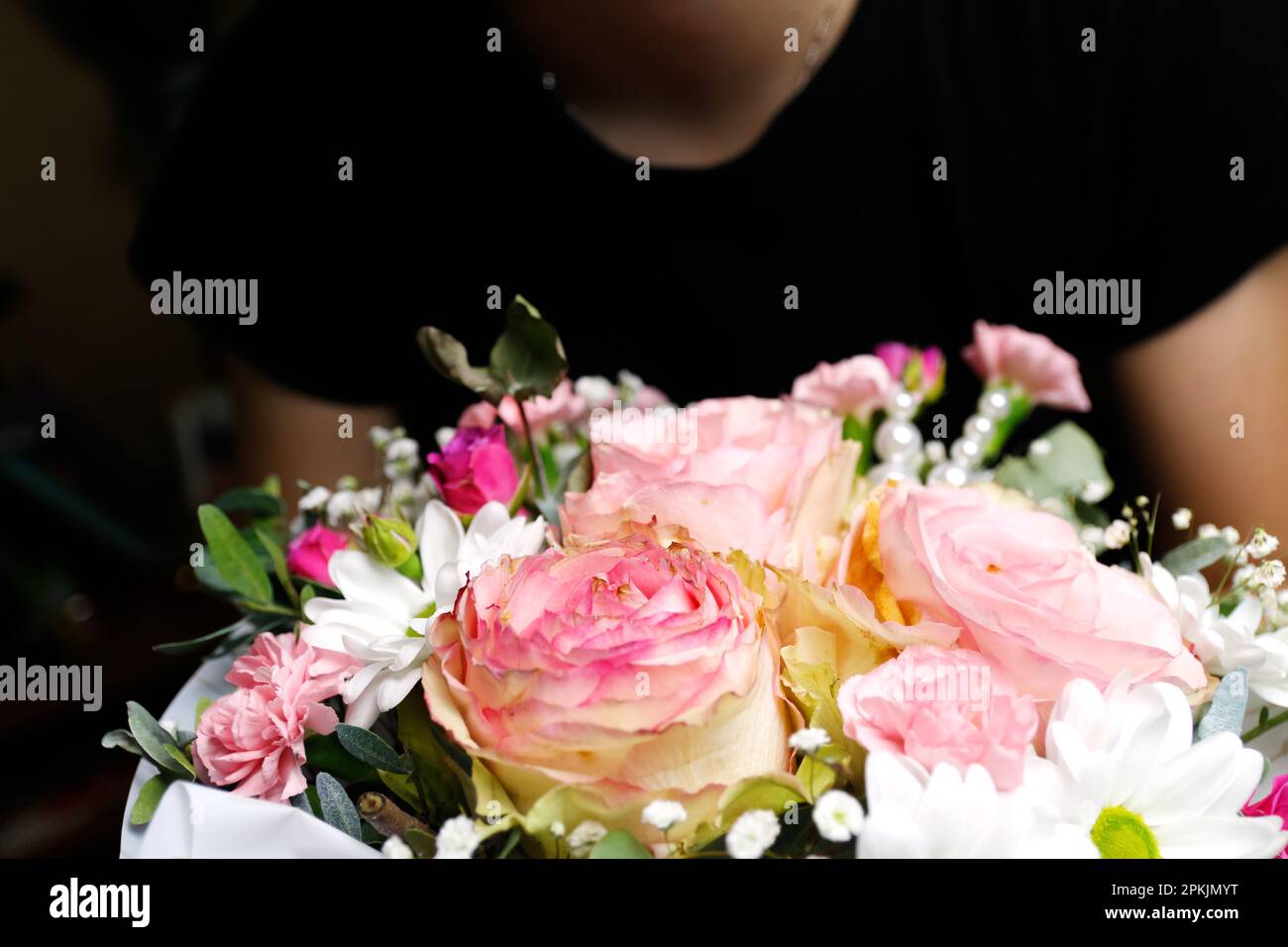 Fleuriste femme tenant un beau bouquet de fleurs aux couleurs rose et vert de roses, pivoine, myrte, feuilles de pistache. Femme présenter bea Banque D'Images